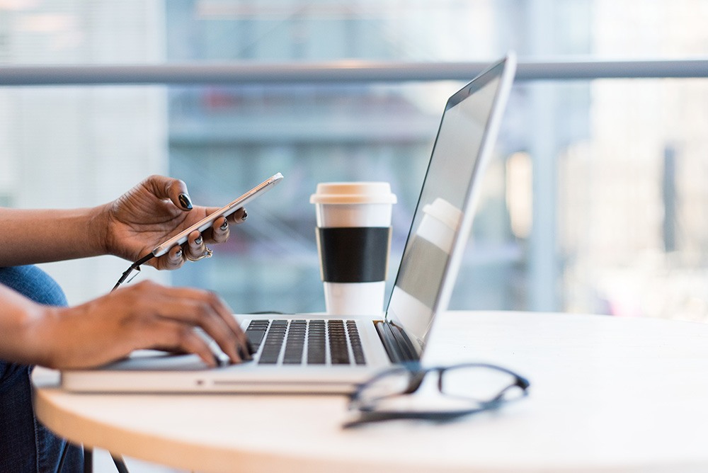 Ein Laptop, an dem man die Hände einer Coworkerin sieht